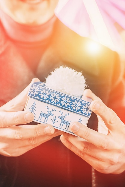 Jonge man met een blauwe en witte geschenkdoos in winterstijl, schittering van de zon