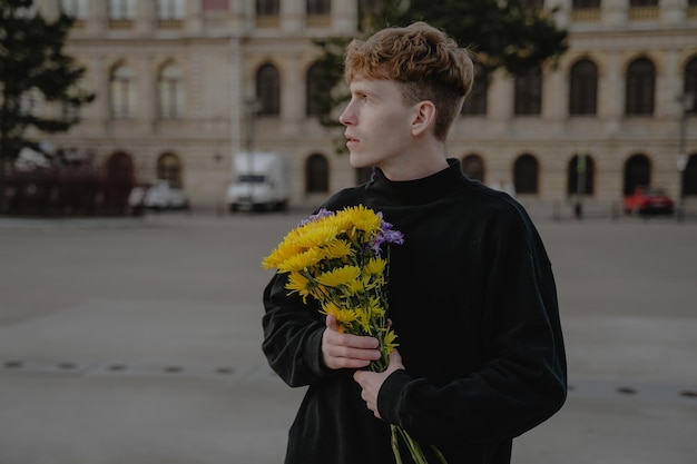 Jonge man met een boeket bloemen kijkt peinzend weg