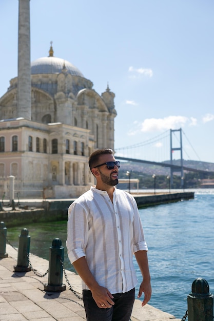 Jonge man met een bril bij de Ortakoy-moskee met de Bosporus-brug in Istanbul