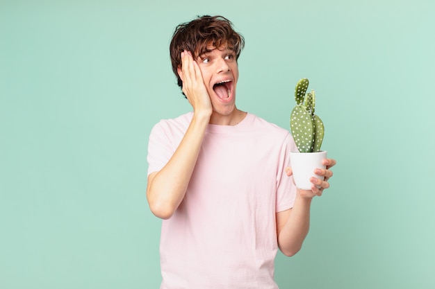 Jonge man met een cactus die zich blij, opgewonden en verrast voelt