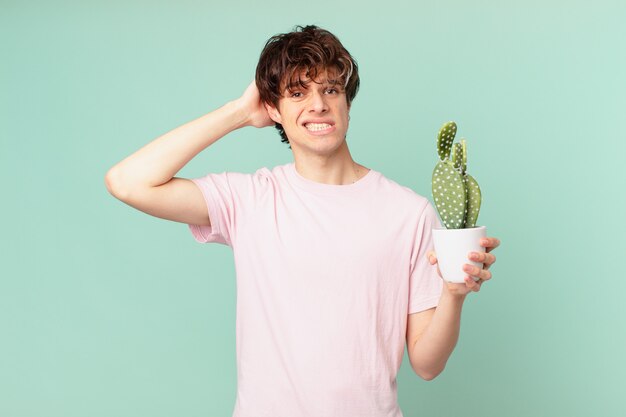 Jonge man met een cactus die zich gestrest, angstig of bang voelt, met de handen op het hoofd