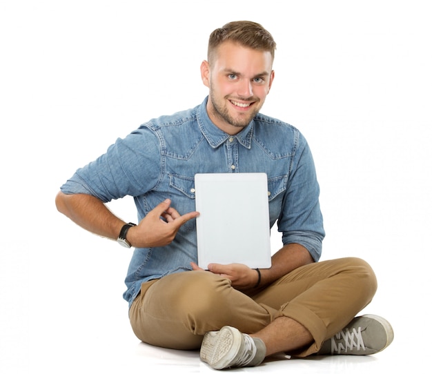 Jonge man met een glimlach van tablet-pc zittend op de vloer