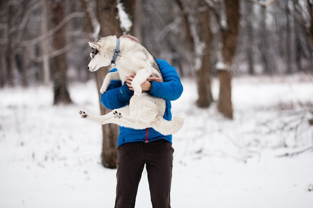 Jonge man met een husky pup in het winter forest. Horizontaal buiten schot.