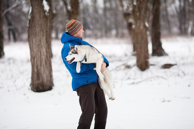 Jonge man met een husky pup in het winter forest. Horizontaal buiten schot.