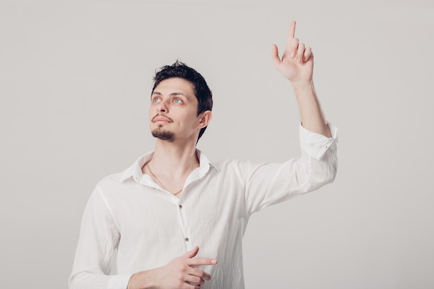 Jonge man met een idee die zijn vinger in de lucht steekt op een grijze achtergrond. gebaar Eureka. zacht licht