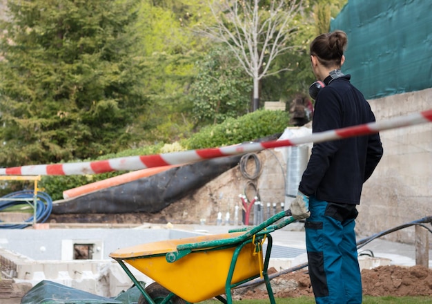 Jonge man met een karretje bezig met de bouw van een zwembad