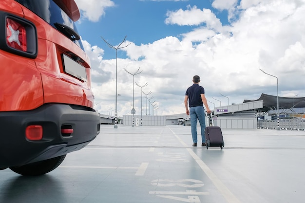 Foto jonge man met een koffer in zijn handen in de parkeerplaats achter uitzicht