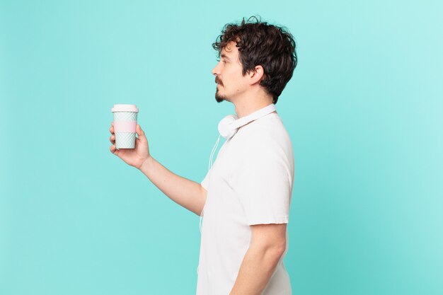 Jonge man met een kopje koffie op profielweergave denken, fantaseren of dagdromen