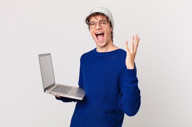 Jonge man met een laptop die zich gelukkig en verbaasd voelt over iets ongelooflijks