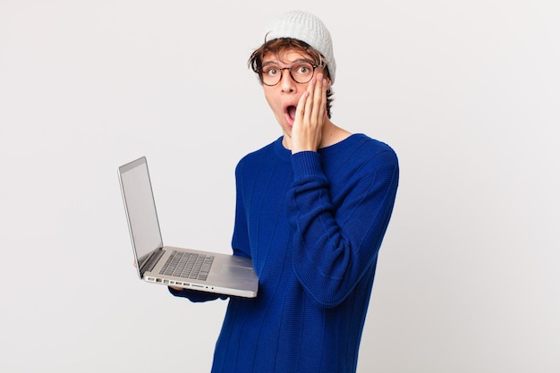 Jonge man met een laptop die zich geschokt en bang voelt