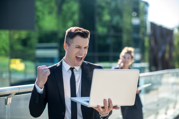 Jonge man met een laptop enthousiast enthousiast