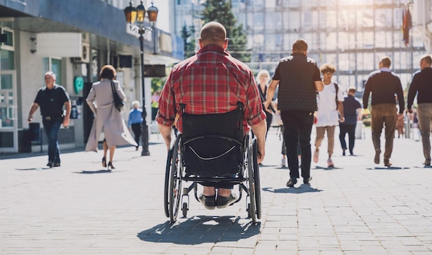 Jonge man met een lichamelijke handicap in een rolstoel loopt op straat