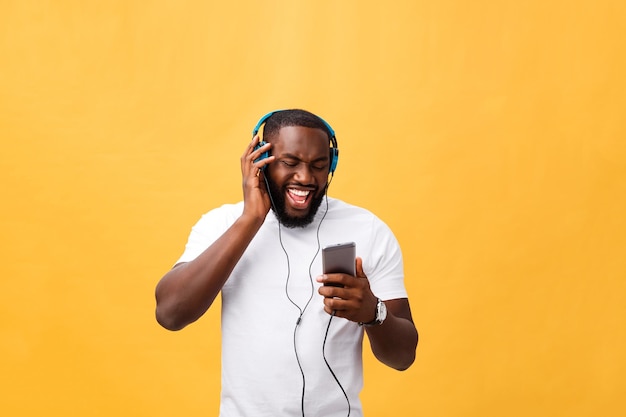 Jonge man met een mobiele telefoon tegen een gele muur.
