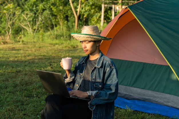 Jonge man met een mobiele telefoon terwijl hij op een tent zit