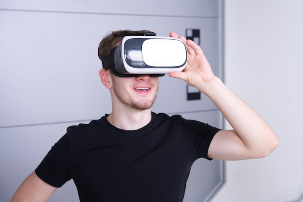 Jonge man met een modern apparaat virtual reality VR-maskerheadset of bril 3D AR-metaverse