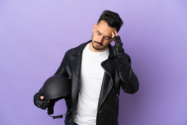 Jonge man met een motorhelm geïsoleerd op paarse achtergrond met hoofdpijn