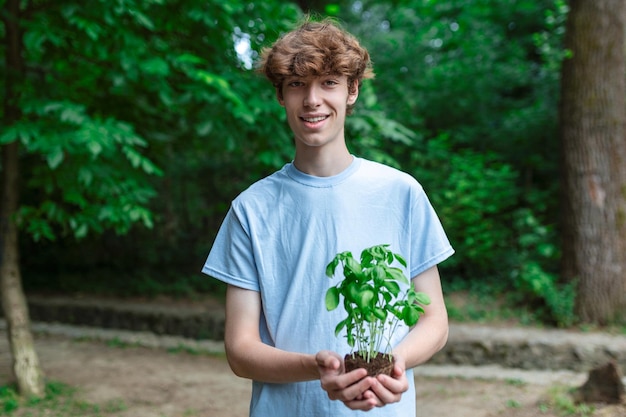 Jonge man met een plant die uit de grond groeit