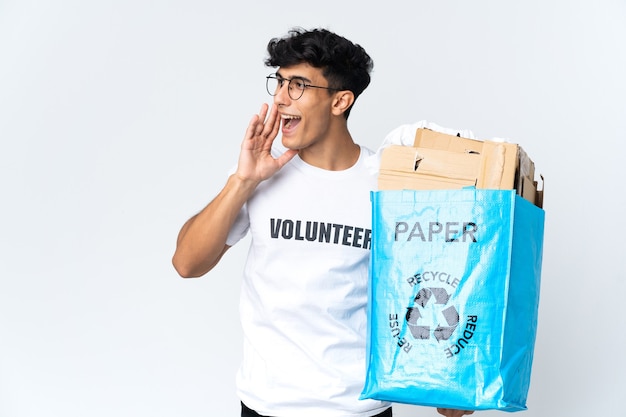 Jonge man met een recycling zak vol papier schreeuwen met wijd open mond aan de zijkant