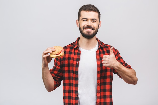 Jonge man met een stuk hamburger. Dieetconcept tegen witte achtergrond wordt geïsoleerd die. Duimen omhoog.