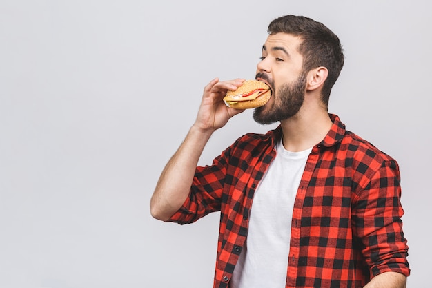 Jonge man met een stuk hamburger. Dieetconcept tegen witte achtergrond wordt geïsoleerd die.