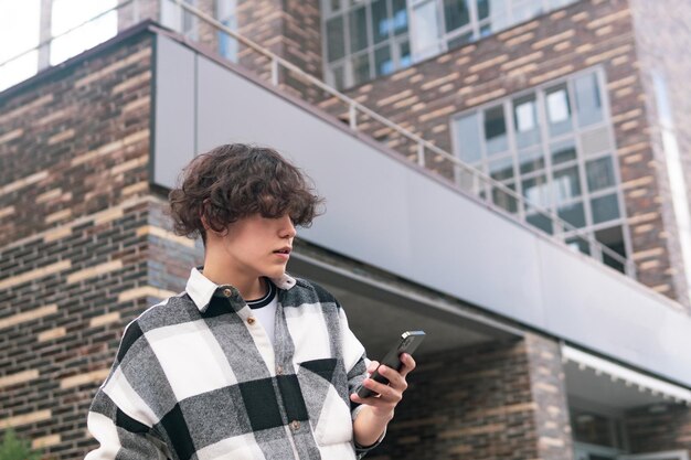 Jonge man met een telefoon op de achtergrond van stadsgebouwen