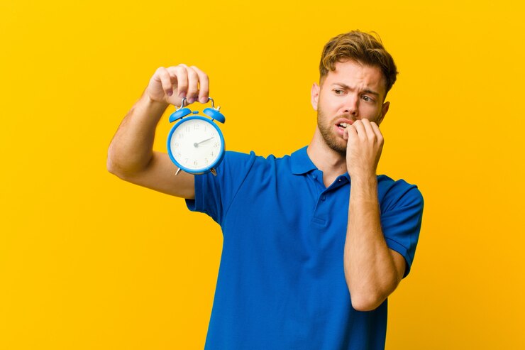 Foto jonge man met een wekker op oranje