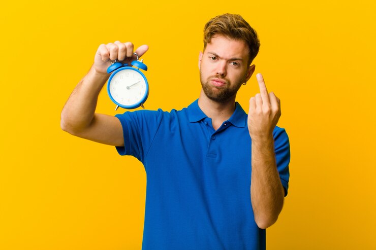Foto jonge man met een wekker tegen oranje achtergrond