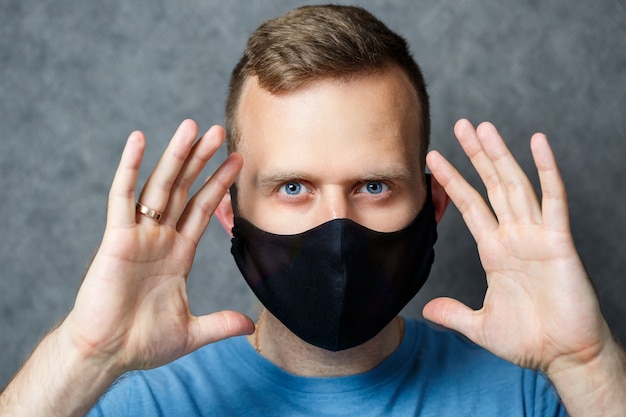 Jonge man met een zwart beschermend medisch masker tegen virussen. COVID 19