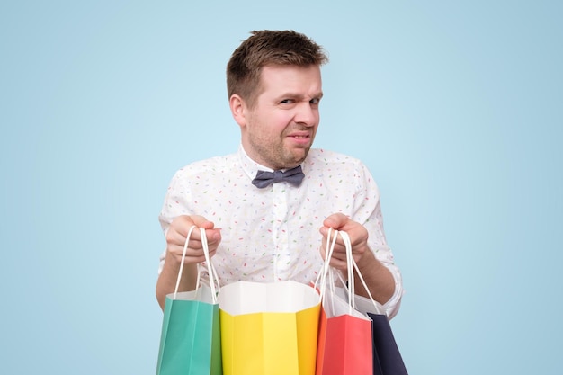 Jonge man met gekleurde papieren pakketten met geschenken