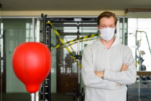 Jonge man met gekruiste armen dragen masker en klaar om te boksen in de sportschool