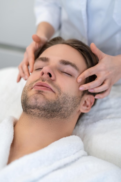 Jonge man met gezichtsmassage in een schoonheidssalon