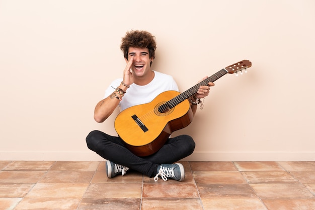 Jonge man met gitaar zittend op de vloer