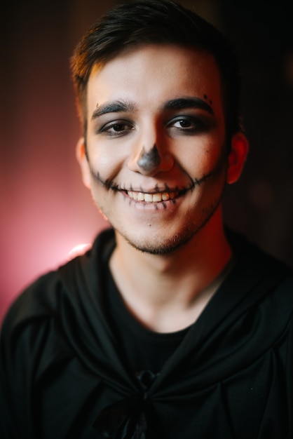 Jonge man met Halloween make-up glimlachen naar de camera. Een close-up van het gezicht van een gelukkige man