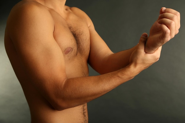 Jonge man met handpijn op grijze achtergrond