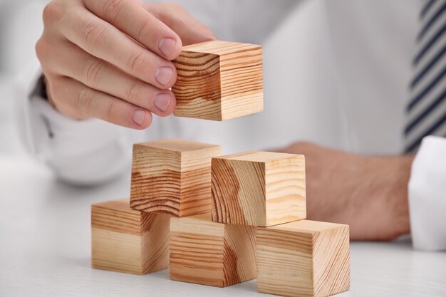 Jonge man met houten blokjes aan tafel