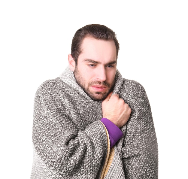 Jonge man met koude gewikkeld in een deken op witte achtergrond