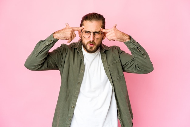 Jonge man met lang haar kijkt gefocust op een taak en houdt de wijsvingers het hoofd gericht.