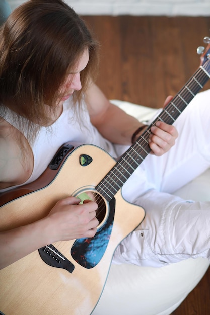 Jonge man met lang haar met een akoestische gitaar