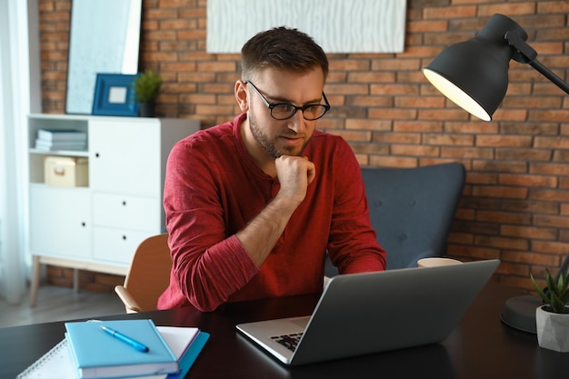 Jonge man met laptop aan tafel binnenshuis