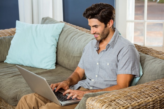 Jonge man met laptop in de woonkamer