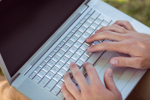 Jonge man met laptop in het park