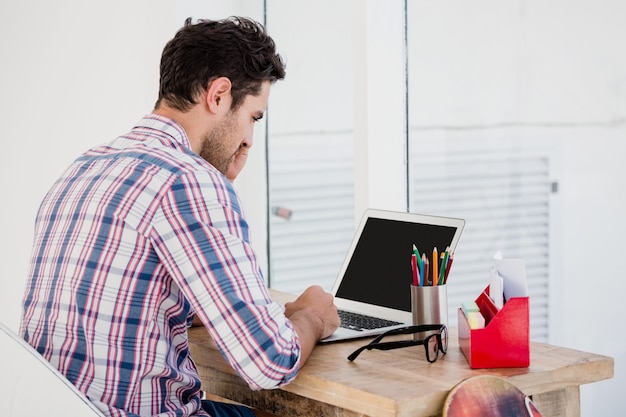 Jonge man met laptop op zijn bureau