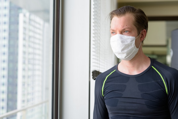 Jonge man met masker voor bescherming tegen uitbraak van het coronavirus, denkend aan sporten tijdens covid-19