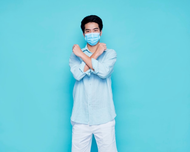 Jonge man met medisch masker op blauwe muur, ruimte voor tekst. Virusbescherming