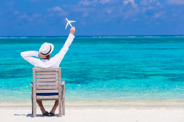 Jonge man met miniatuur van een vliegtuig op tropisch strand