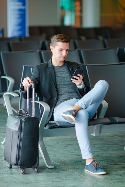 Jonge man met mobiel op de luchthaven tijdens het wachten op instappen.