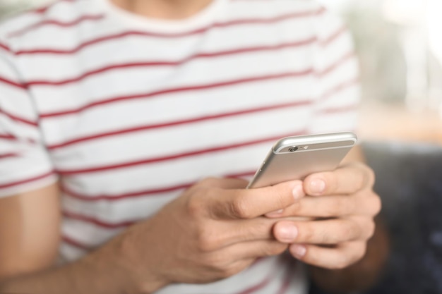 Jonge man met mobiele telefoon binnenshuis