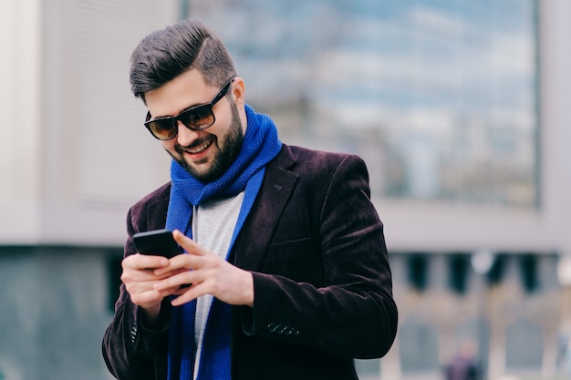 Jonge man met mobiele telefoon in de straat