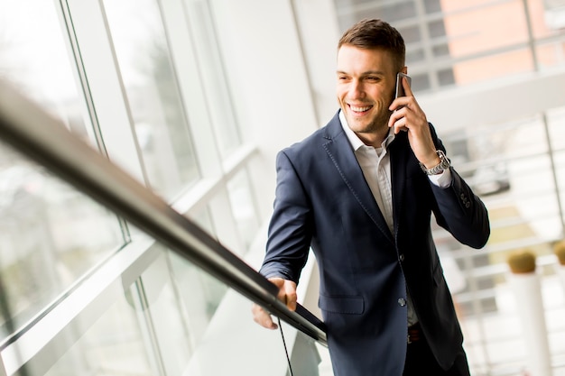 Jonge man met mobiele telefoon op kantoor