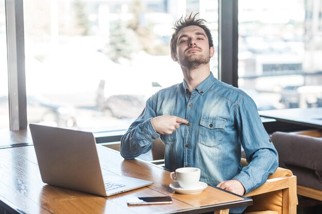 Foto jonge man met mobiele telefoon terwijl hij op tafel zit